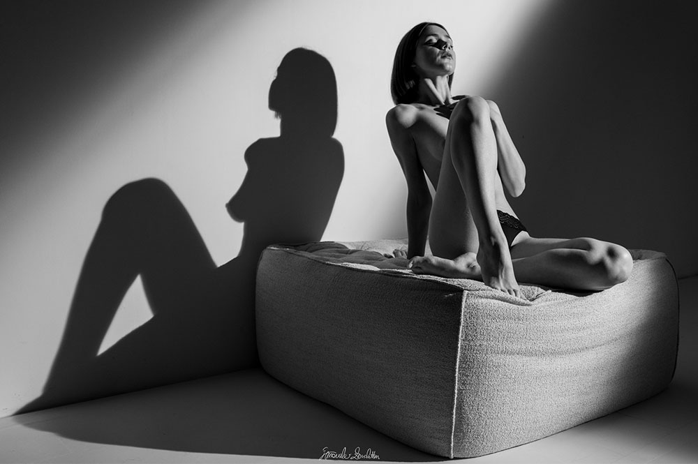 Figura seduta in bianco e nero con una grande ombra sulla parete