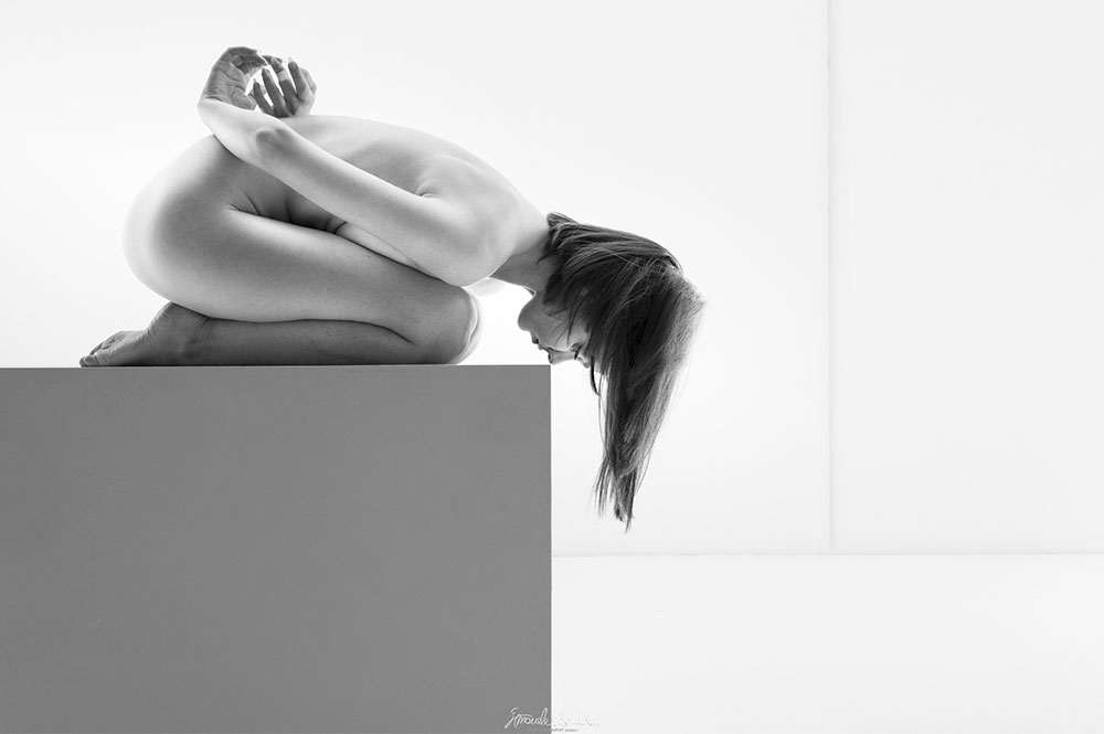 Studio high-key di figura raccolta su un piedistallo quadrato