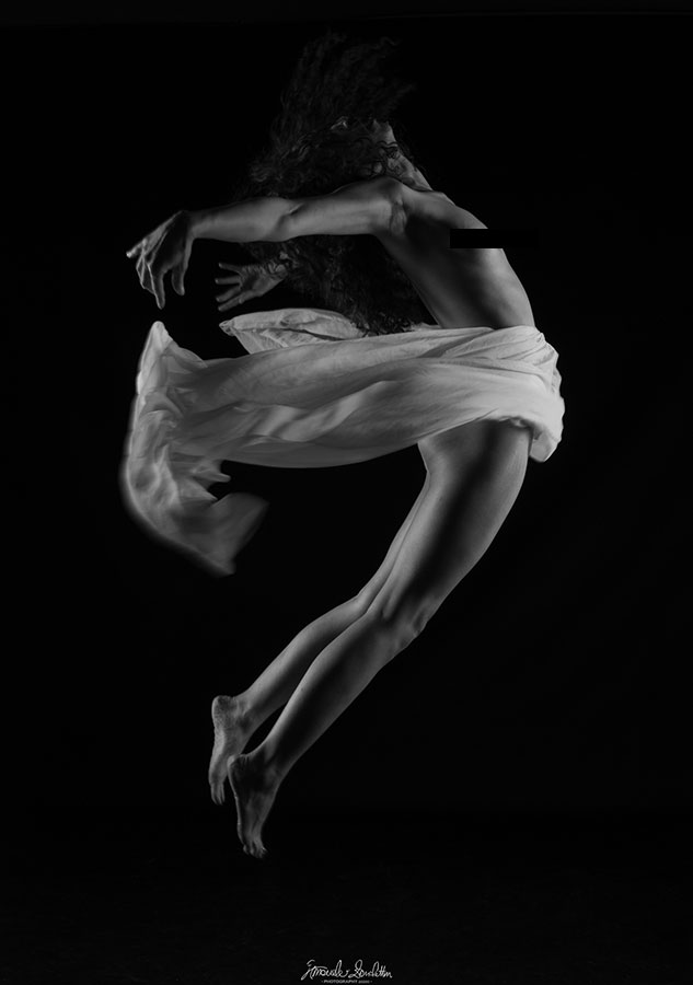 Ritratto in bianco e nero di una ballerina che salta con il tessuto in movimento