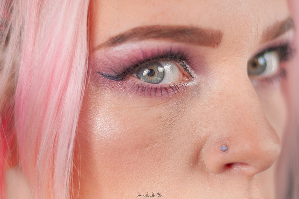 Dettaglio ravvicinato di un occhio con capelli rosa e trucco occhi metallizzato