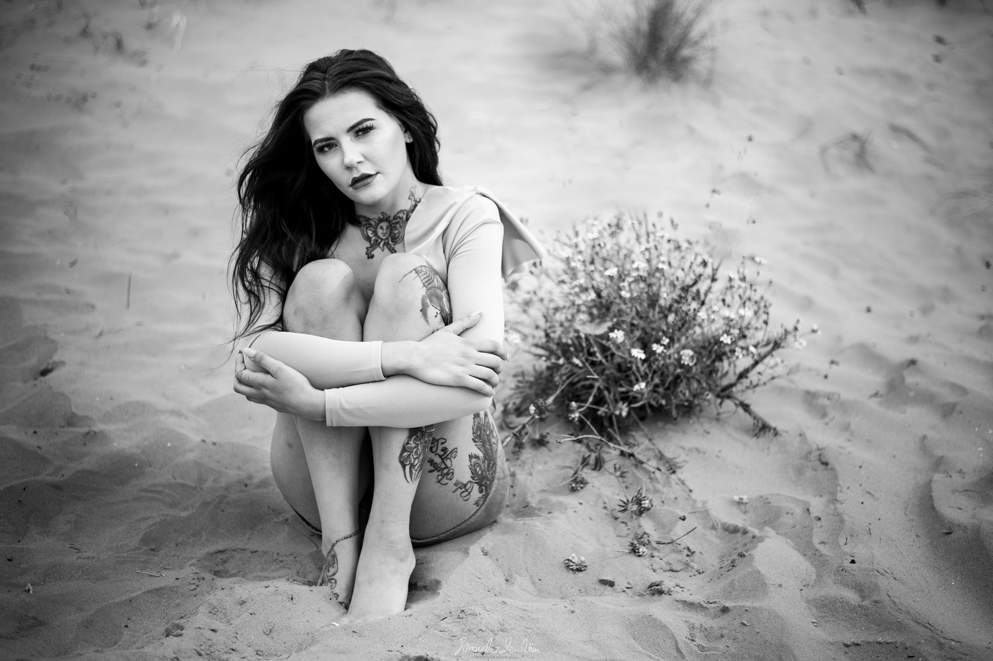 Black and white seated portrait on sand
