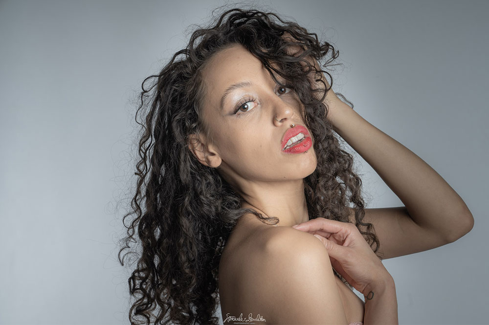 Bare-shouldered close portrait with dark curls and red lipstick