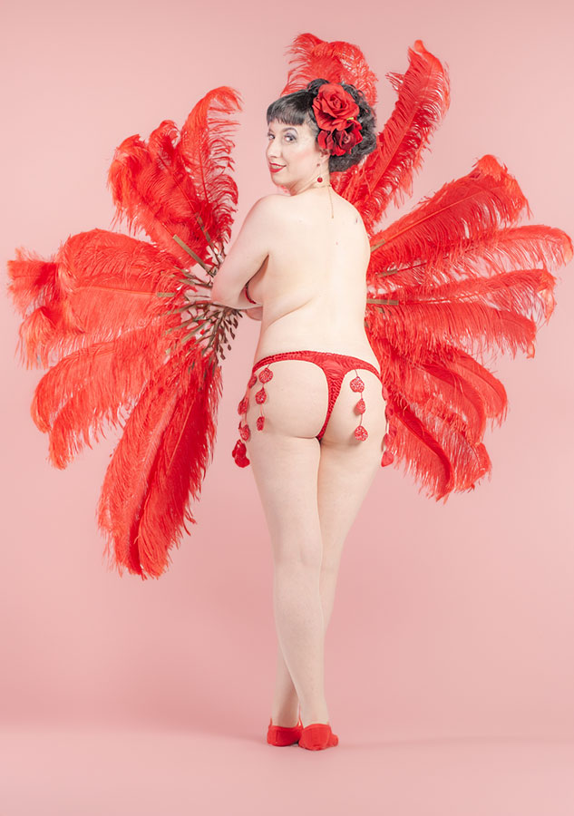 Full-length portrait with a red feather fan and matching costume