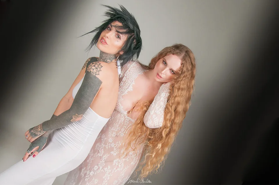 Two portrait subjects in white and red corsetry in angled light