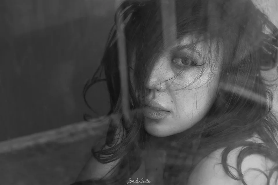 Layered black-and-white close portrait behind translucent fabric