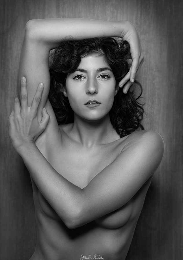 Black-and-white seated figure with arms framing the head and torso