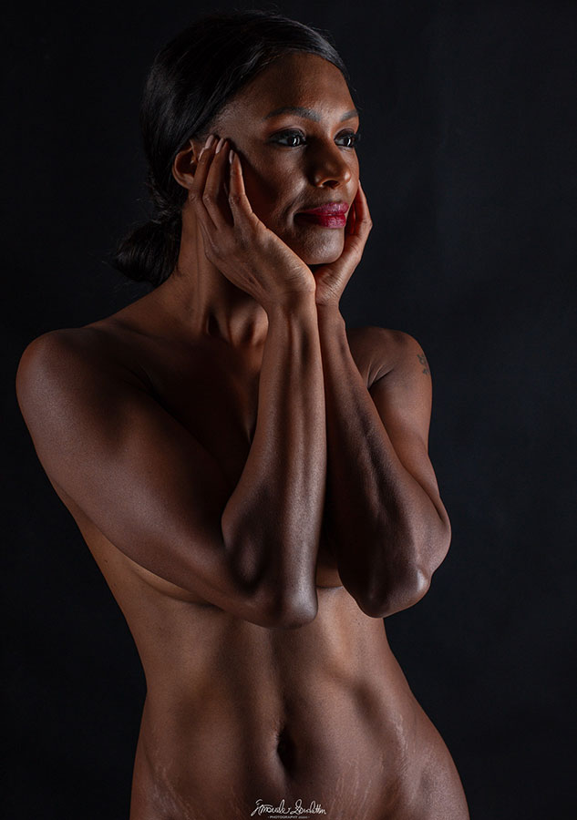 Low-key close portrait with both hands framing the face